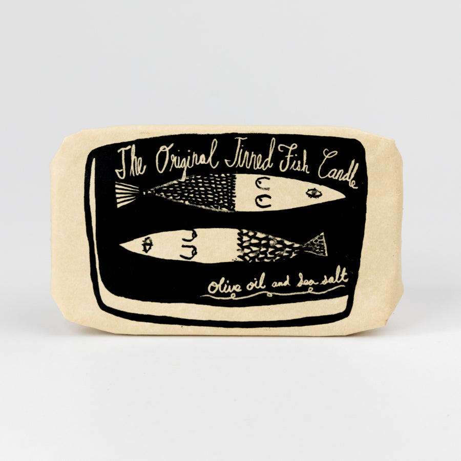 Rectangular packaging of candle with fish design and text on a light gray background