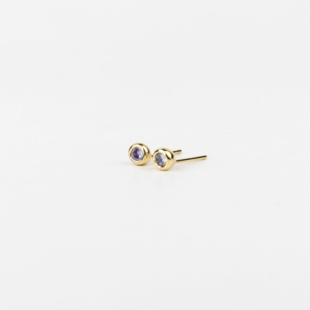 Gold stud earrings with purple gemstones on a white background
