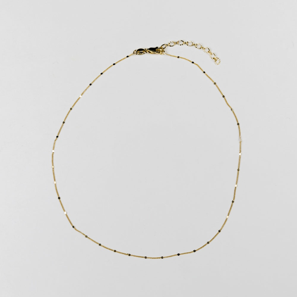 Delicate gold necklace on a light gray background