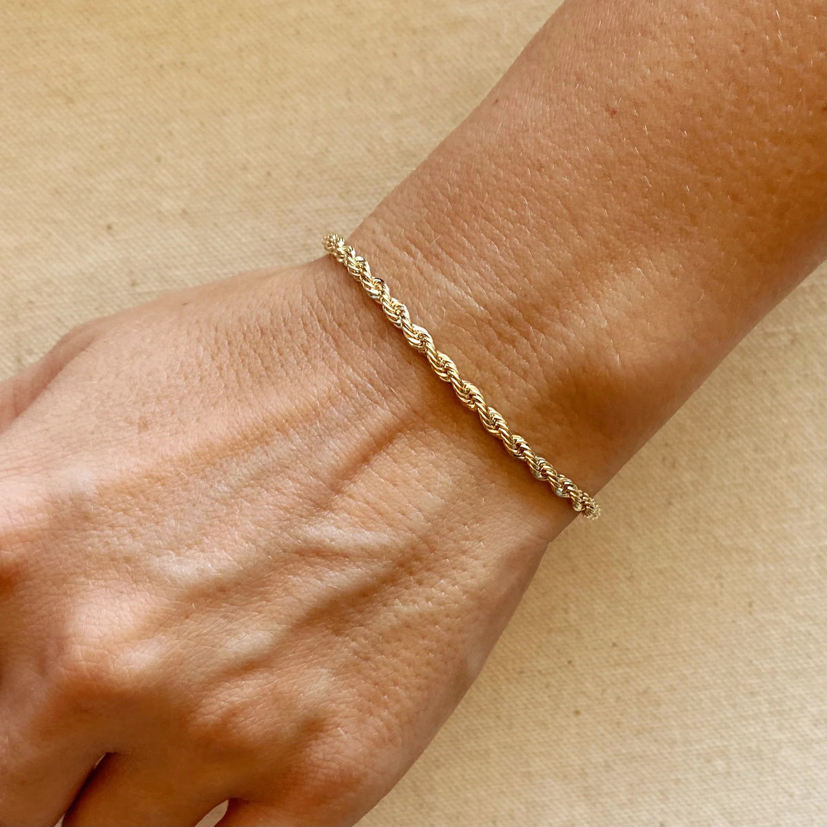 Gold chain bracelet on a light gray background