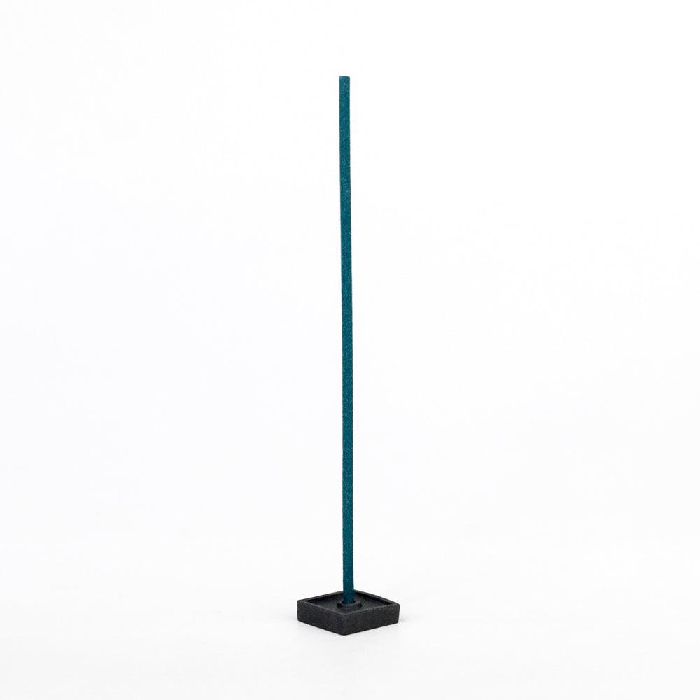 Teal incense with black square holder on a white background